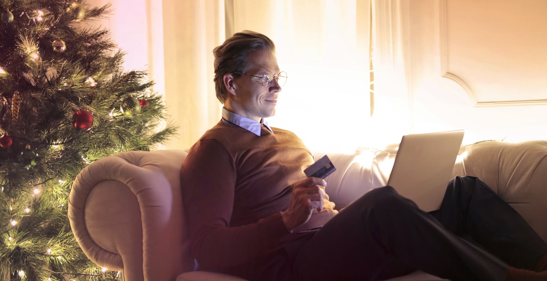 Man on sofa with credit card in hand presumably internet shopping