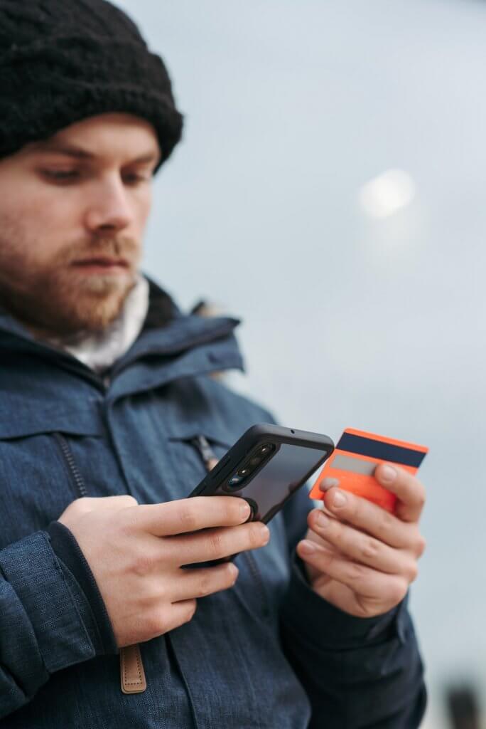man holding a phone and a credit card
